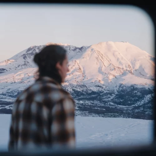 Tim looking into the scenery of snow covered mountains dipped into golden sun light.