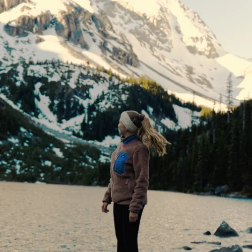 Girl at mountain lake. Snowy mountains surrounding.